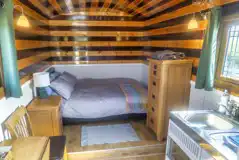 Shepherd's hut interior with a double bed, storage units, and a kitchenette Shepherd's hut interior with a double bed, storage units, and a kitchenette