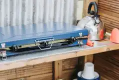 Bell tent camp kitchen with a gas stove, kettle and crockery