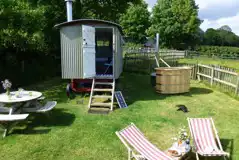 The Shepherd's Hut exterior with hot tub, seating and deck chairs