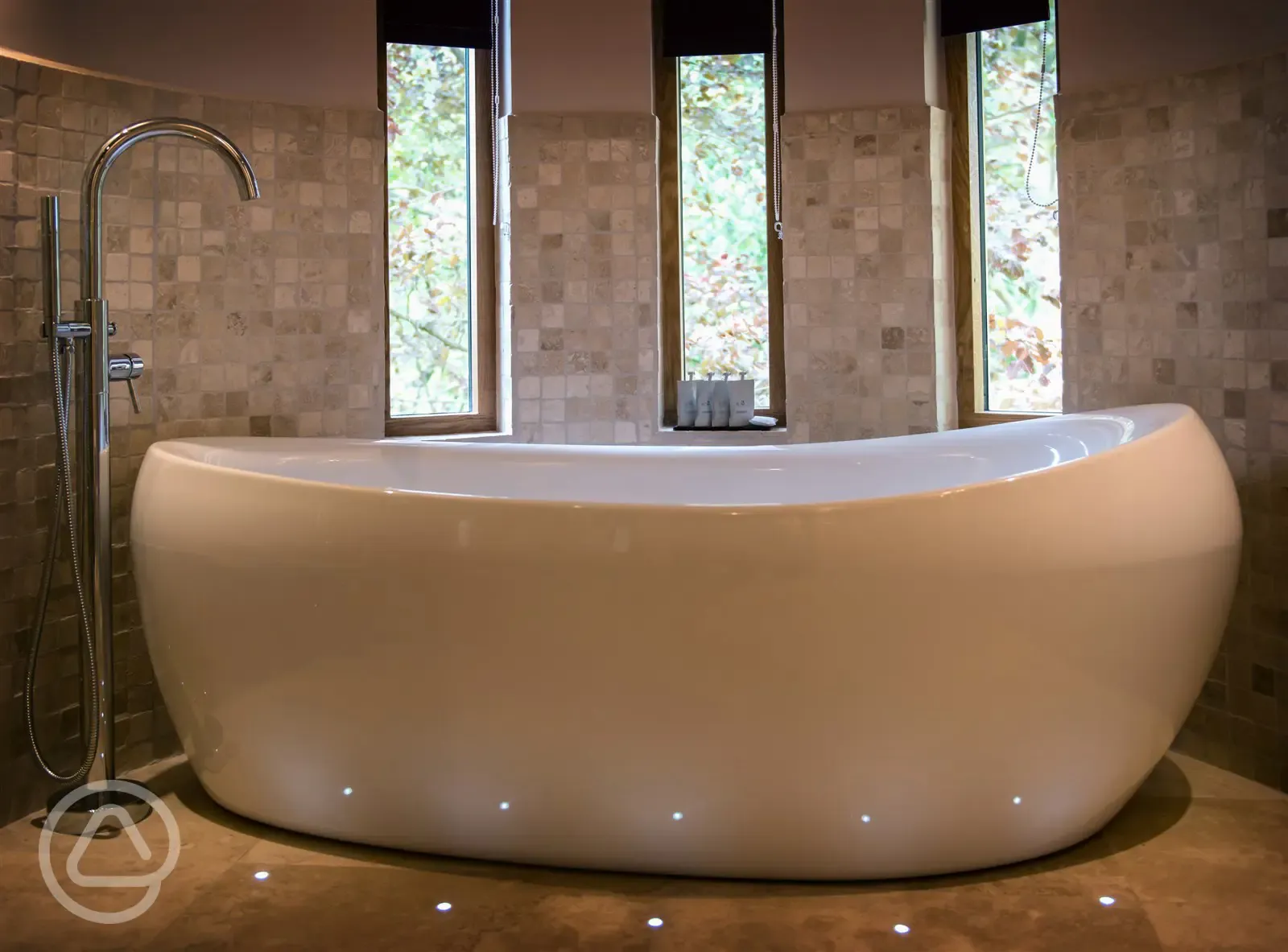 Stand alone deep fill bathtub surrounded by floor moodlighting.