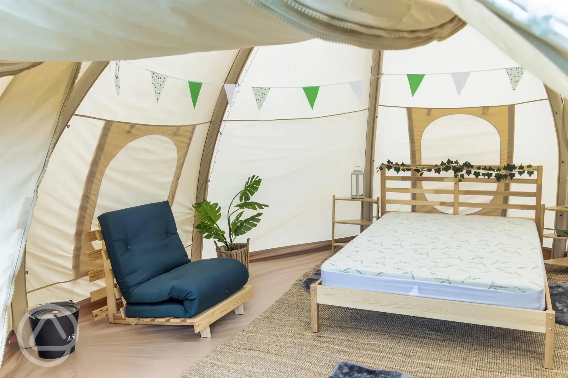 Bell tent interior with double bed, chair with sleeping mat and LED lighting