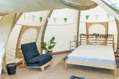 Bell tent interior with double bed, chair with sleeping mat and LED lighting Bell tent interior with double bed, chair with sleeping mat and LED lighting