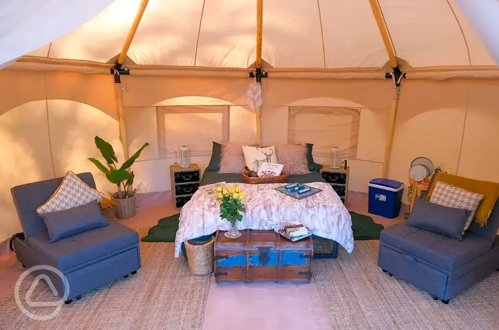Bell tent interior with a double bed and two single futon beds (bring bedding)