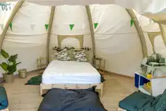 Bell tent interior with a double bed and two single futon beds (bring bedding)