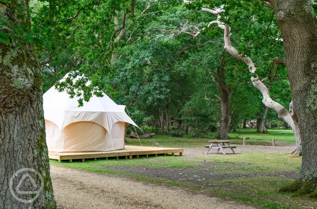 Bell tents set on wooden deckings with private picnic benches
