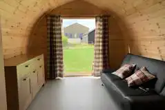 Camping pod interior with a double sofa and storage space