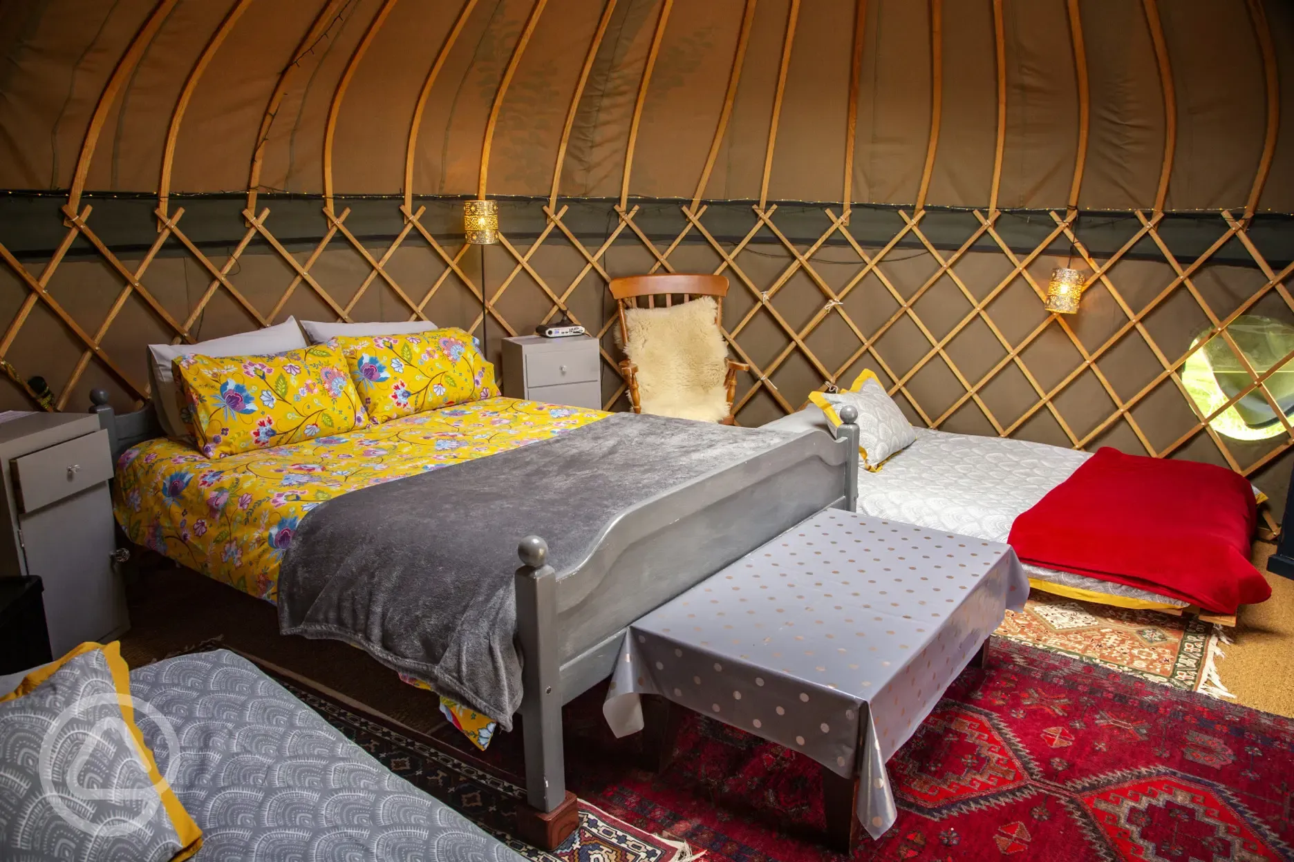King size bed in daisy Yurt, comfy chair and sheepskin rug