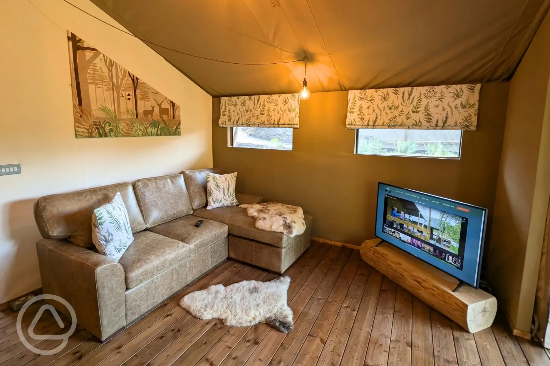 Luxury adult only safari tent interior with an L-shaped sofa and TV