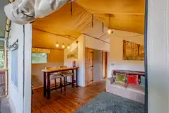 Luxury adult only safari tent interior with an L-shaped sofa and dining area Luxury adult only safari tent interior with an L-shaped sofa and dining area