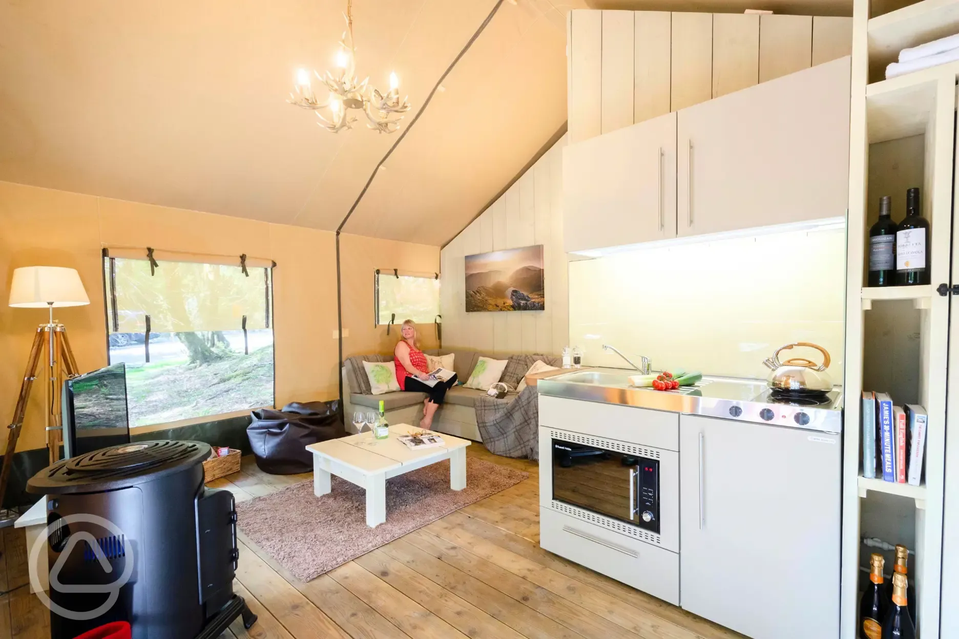 Safari tent interior with a sofa, wood burner and kitchen