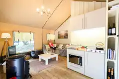 Safari tent interior with a sofa, wood burner and kitchen