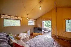 Luxury adult only safari tent interior with an L-shaped sofa, heater and TV
