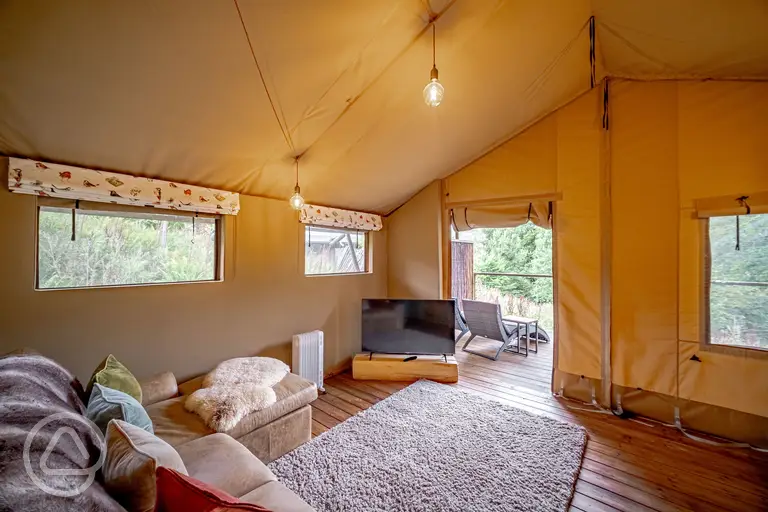 Luxury adult only safari tent interior with an L-shaped sofa, heater and TV