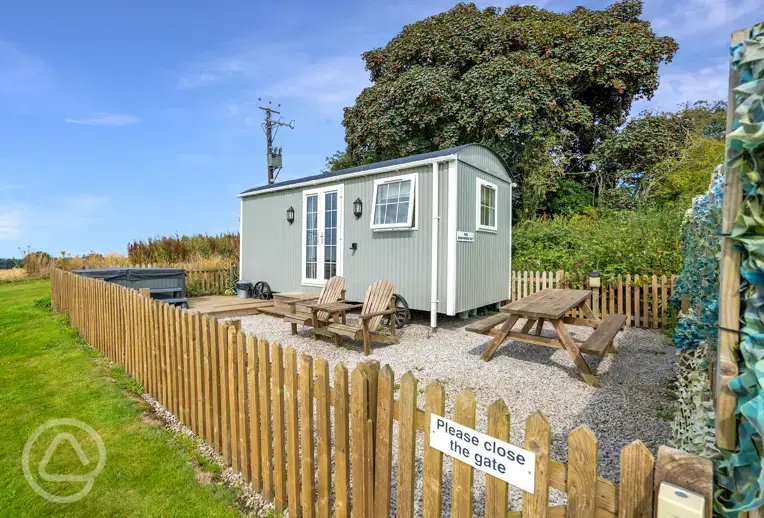 The hut with a gated garden area, seating and electric hot tub