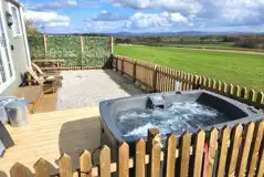 The hut gated garden area with seating, a deck and electric hot tub