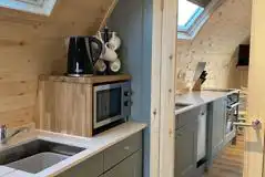 Mega ensuite glamping pod kitchen area with microwave, kettle, and crockery