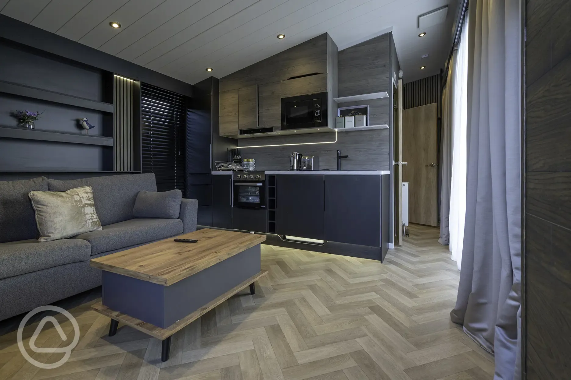 Glamping S-pod living area with sofa, kitchen and TV