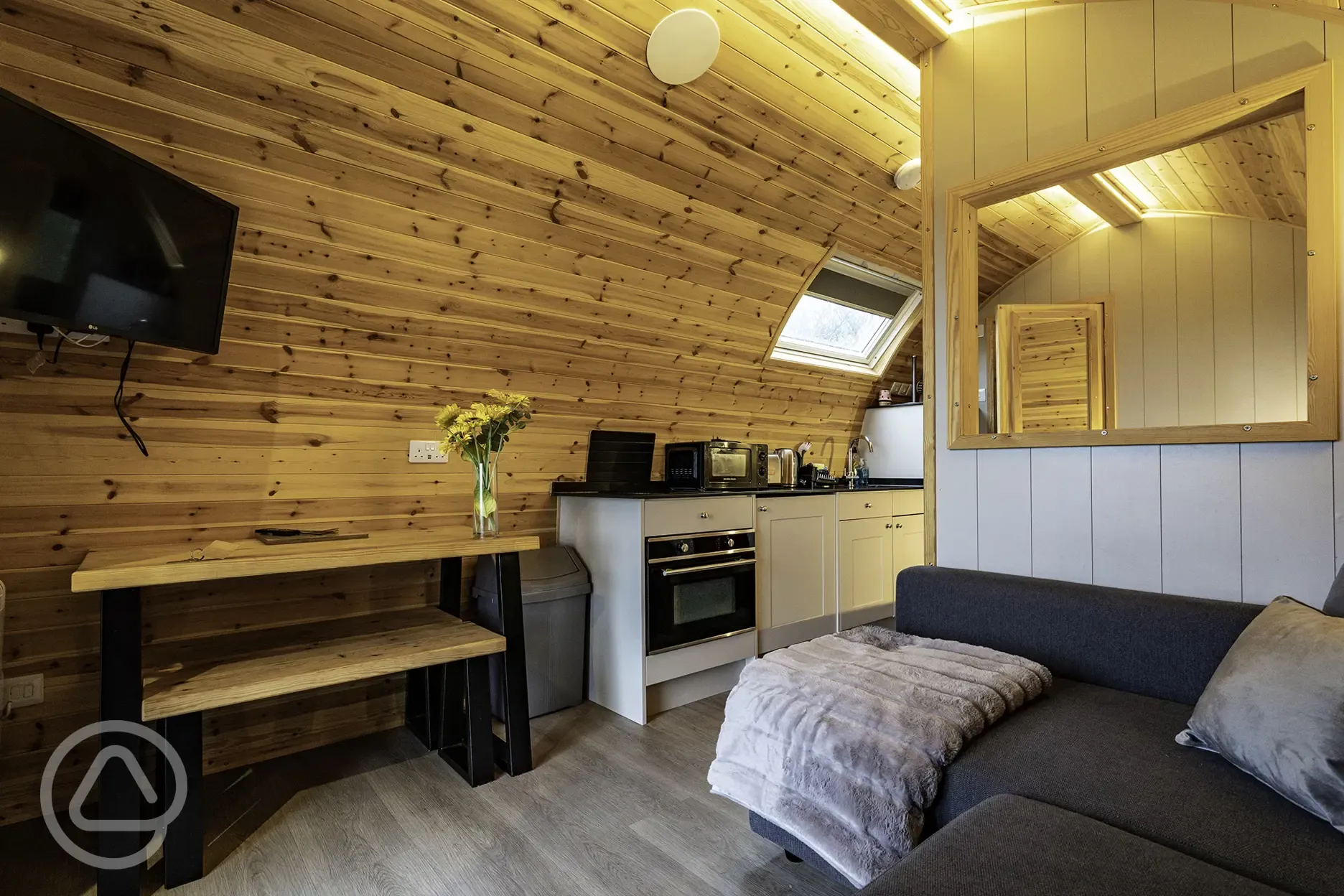 Mega glamping pod interior with a sofa bed, TV and kitchen