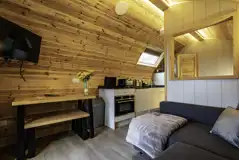 Mega glamping pod interior with a sofa bed, TV and kitchen