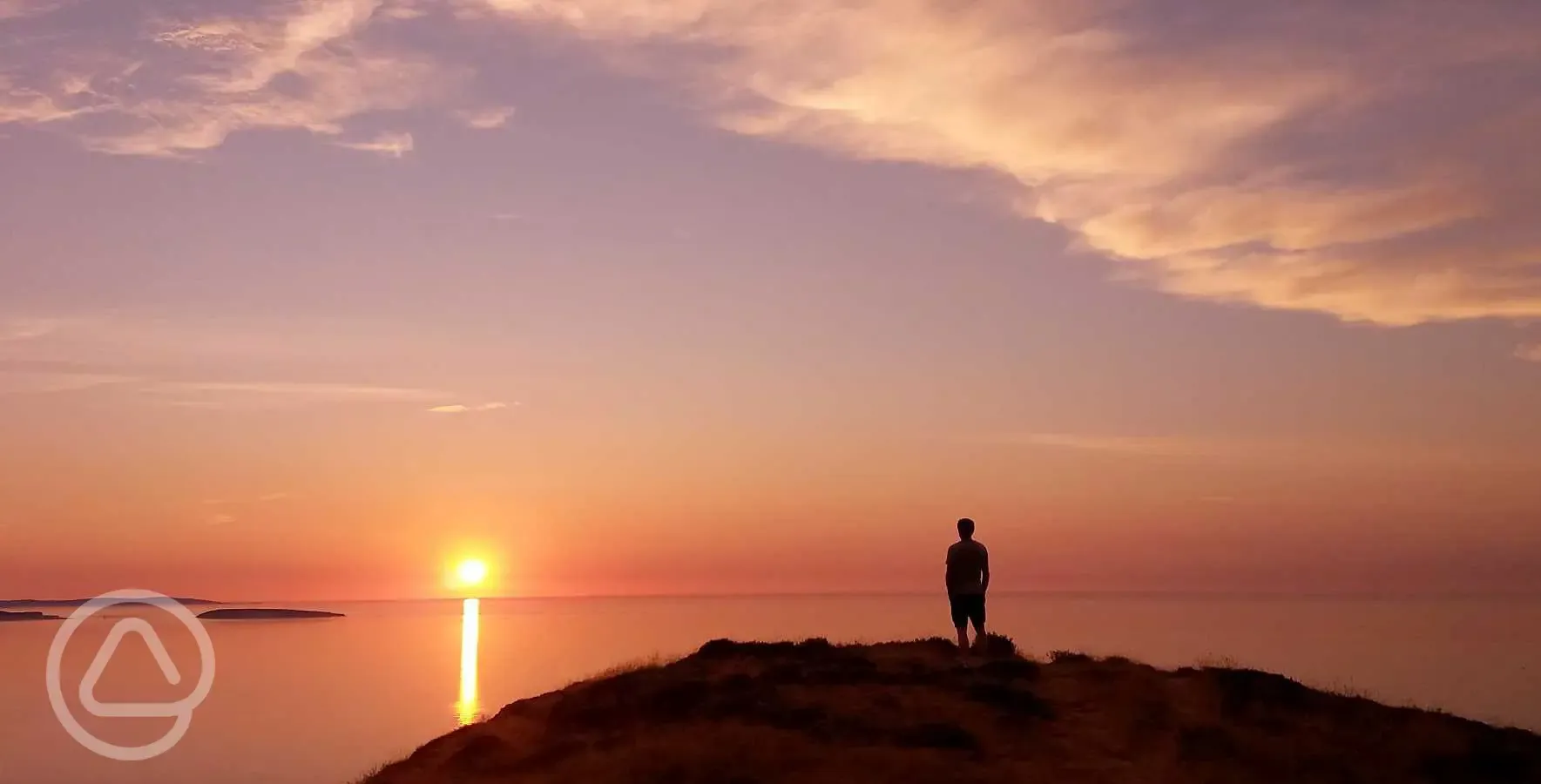 Sunset over Trwyn yr Wylfa Camping Site pitches and the sea