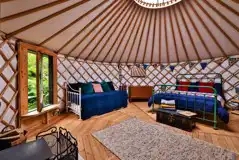Bert the yurt interior with a king bed, two singles, and a sofa bed Bert the yurt interior with a king bed, two singles, and a sofa bed