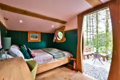 Cosy woodland cabin interior with a double bed (bedding) and furnishings Cosy woodland cabin interior with a double bed (bedding) and furnishings