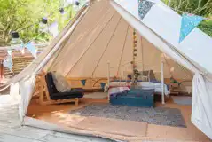 Bluebell bell tent interior with a double bed and two futon beds
