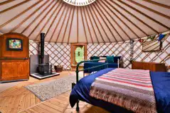 Bert the yurt interior with a double bed, two singles, and a sofa bed Bert the yurt interior with a double bed, two singles, and a sofa bed