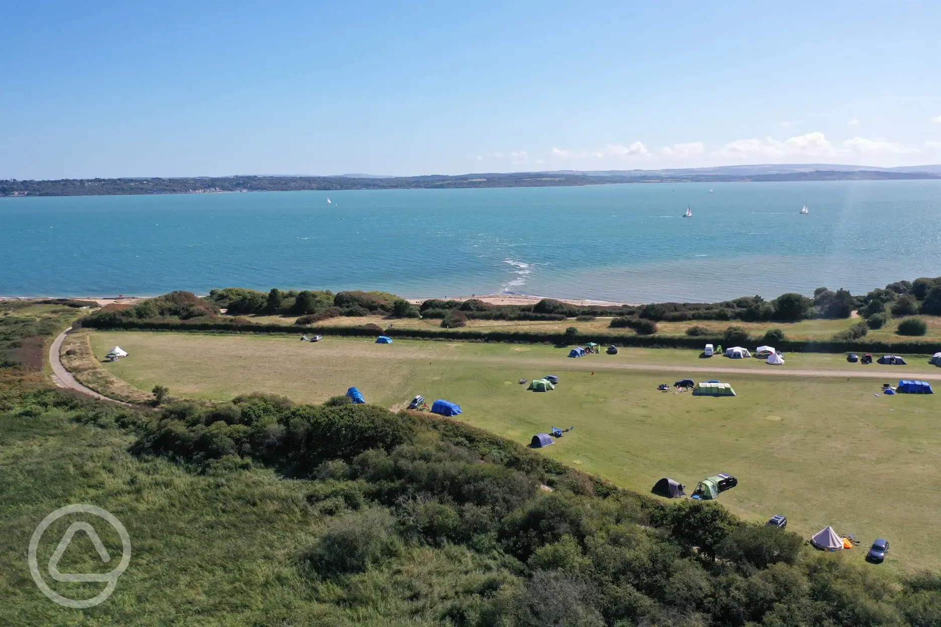 Aerial view of the non electric grass tent pitches and the sea