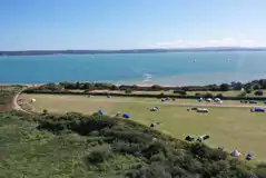 Aerial view of the non electric grass tent pitches and the sea