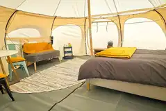 Stargazer bell tent interior with seating and double bed Stargazer bell tent interior with seating and double bed