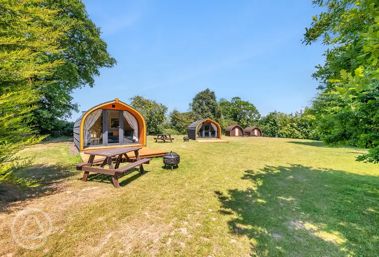 Glamping pods exterior with picnic tables and fire pits