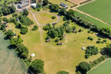 Aerial of grass pitches and glamping pods