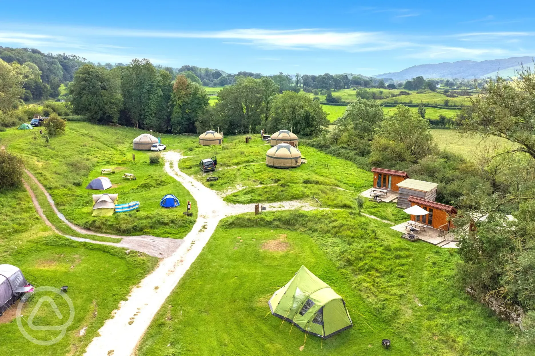 Grass pitches, yurts and mini lodge pods surrounded by trees