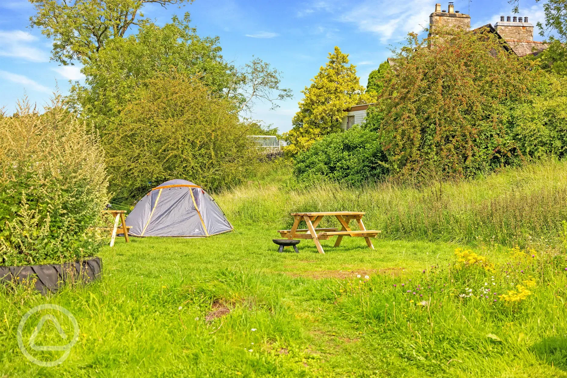 Premium non electric grass tent pitches with a picnic bench and fire pit