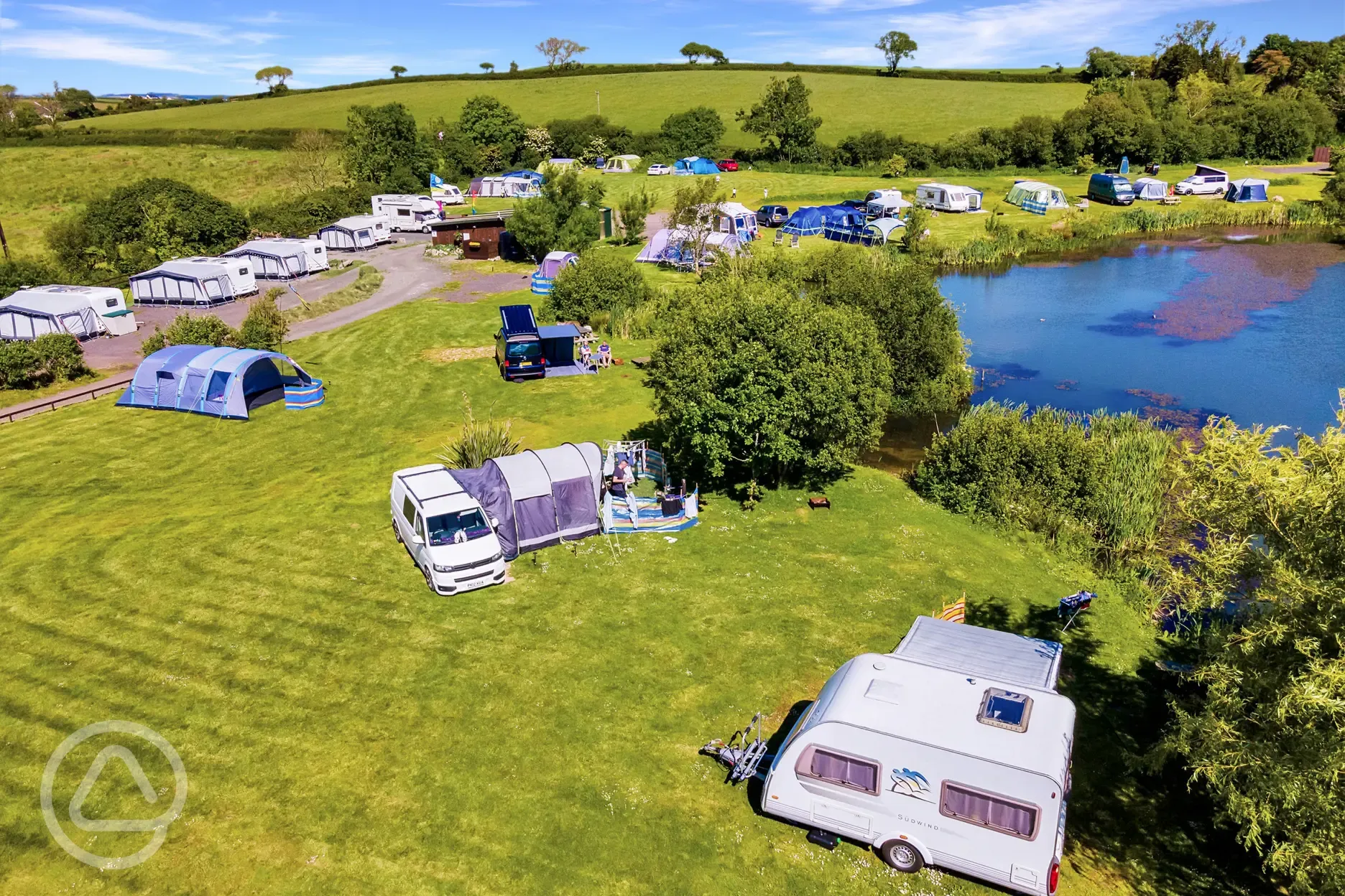 Caravan, motorhomes, and tents on electric lake view grass pitches