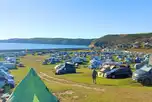 Tents and tourers on grass pitches at Newgale Campsite with sea views