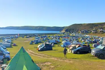 Tents and tourers on grass pitches at Newgale Campsite with sea views