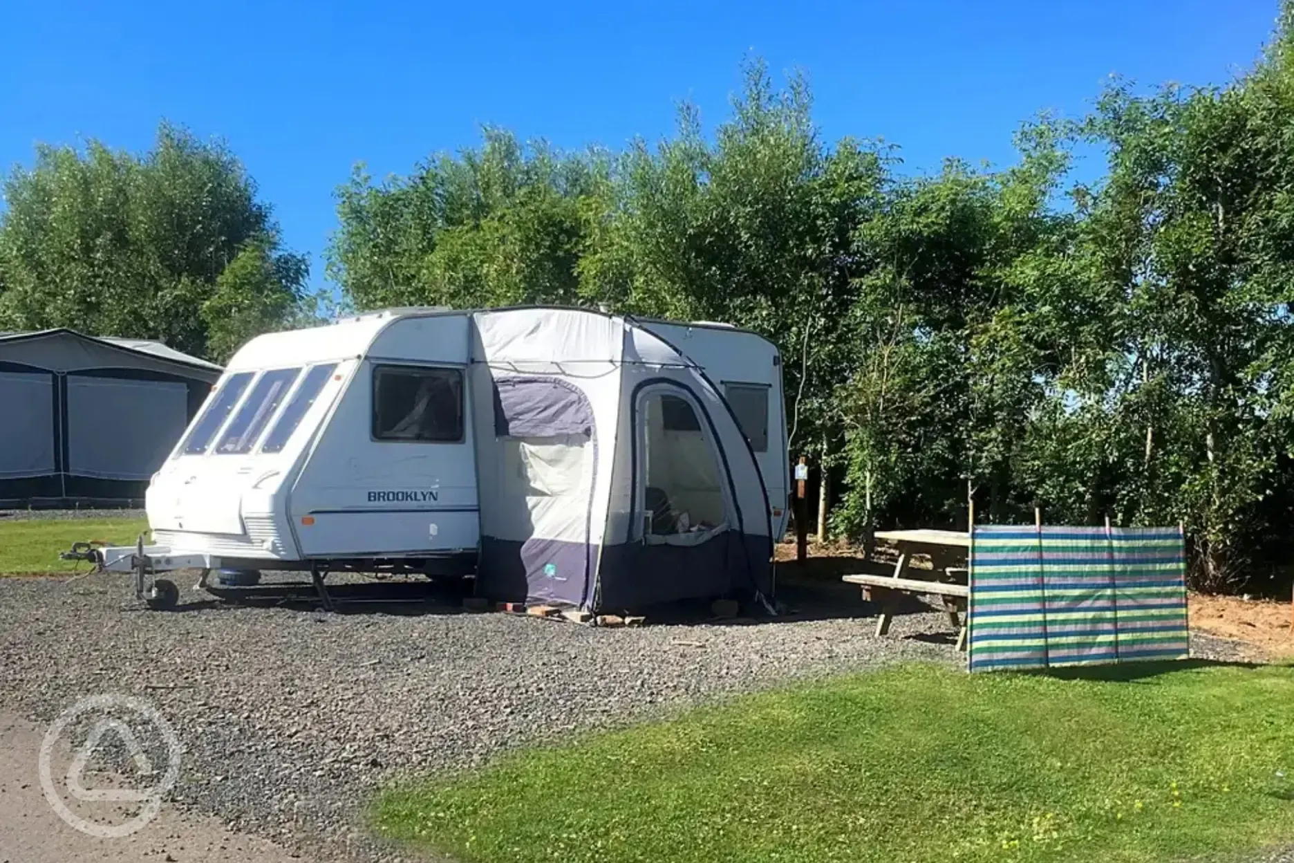 Caravan with an awning and picnic bench on an electric hardstanding pitch