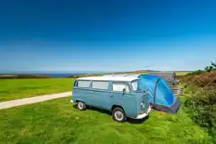 Large tent on grass pitch with space for a parked car