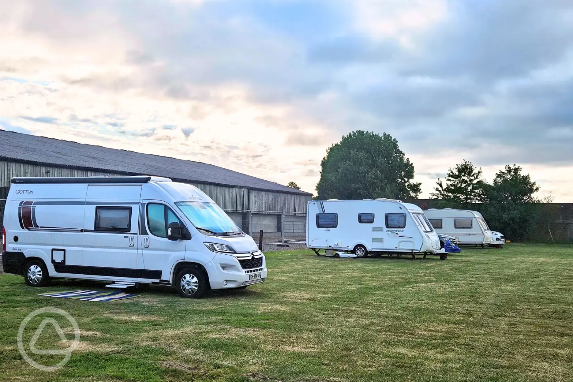 Motorhome and caravans on the Robin electric grass pitches by farm buildings