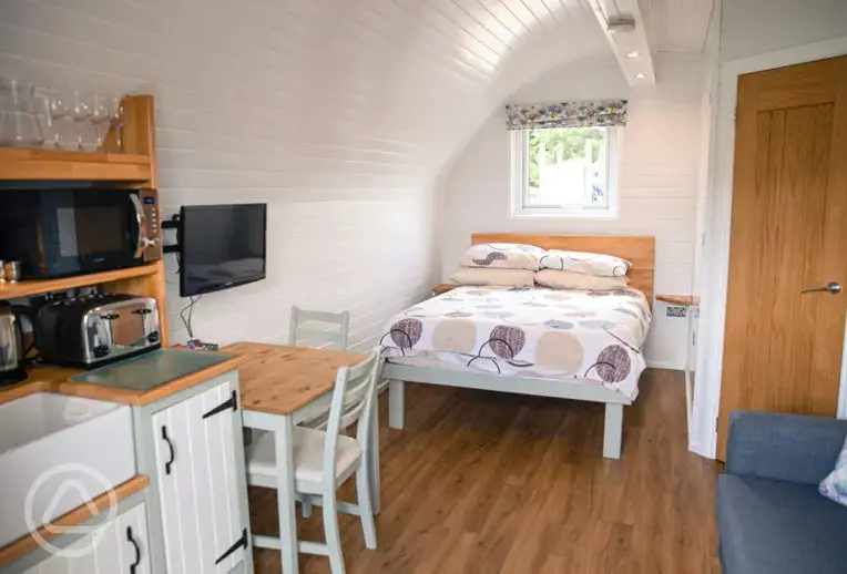 Glamping pod interior with double bed, ensuite, kitchenette and living space