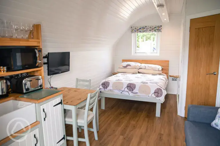 Glamping pod interior with double bed, ensuite, kitchenette and living space
