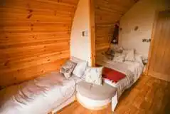 Glamping pod interior with a double bed and single sofa beds