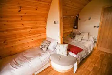 Glamping pod interior with a double bed and single sofa beds