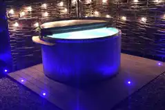 Ensuite glamping pod hot tub at night with fairy lights
