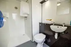 Bell tent private facilities with a toilet, shower, and handwashing sink