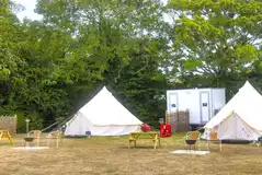 Furnished bell tents with private facilities and a fire pit at Buckland Campsite