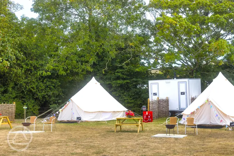 Furnished bell tents with private facilities and a fire pit at Buckland Campsite