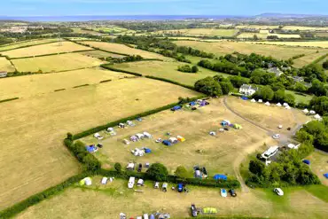 Aerial view of the pitches at Buckland Campsite with distant sea views